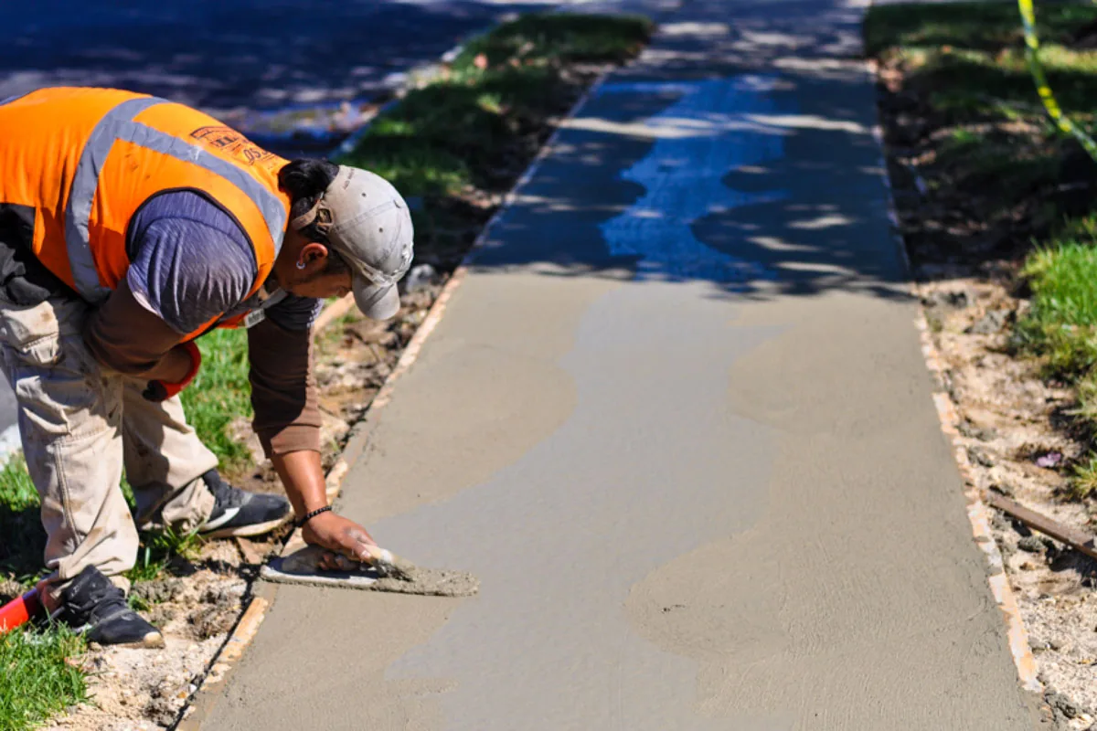 person smoothing out a concrete sidewalk